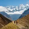Hikers walking in Tsum Valley with snowy peaks.