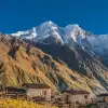 Rustic stone houses with snow-capped mountain in Tsum Valley, Manaslu Circuit.