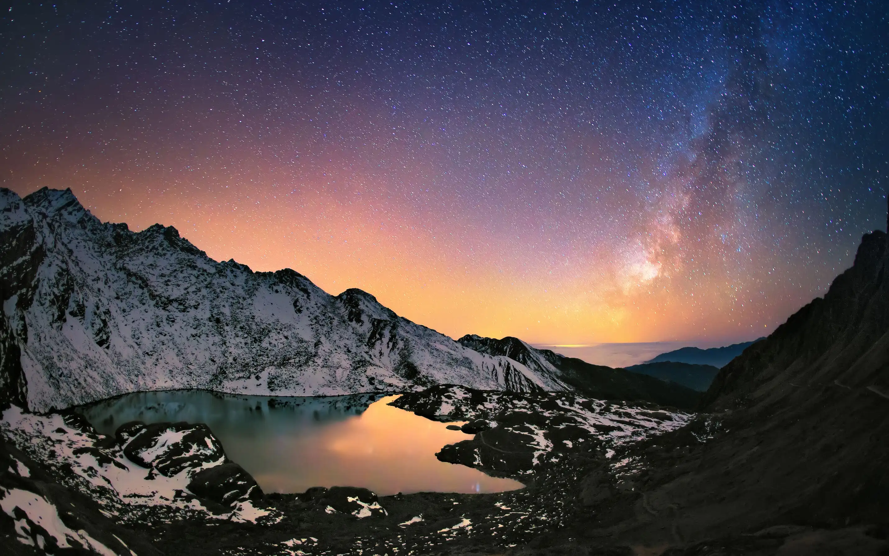 Starry night with the Milky Way above snowy mountains reflected in the calm Gosainkunda Lake at twilight.