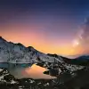 Starry night with the Milky Way above snowy mountains reflected in the calm Gosainkunda Lake at twilight.