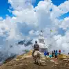 Person on horseback and hikers near a white stupa on a cloudy mountain ridge in Helambu.