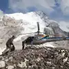 Helicopter on rocky snowy mountain with people in outdoor gear approaching (Everest Base Camp Heli Tour).