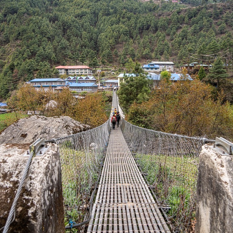 Suspension bridge on the trail to Phakding with trekkers crossing toward the village