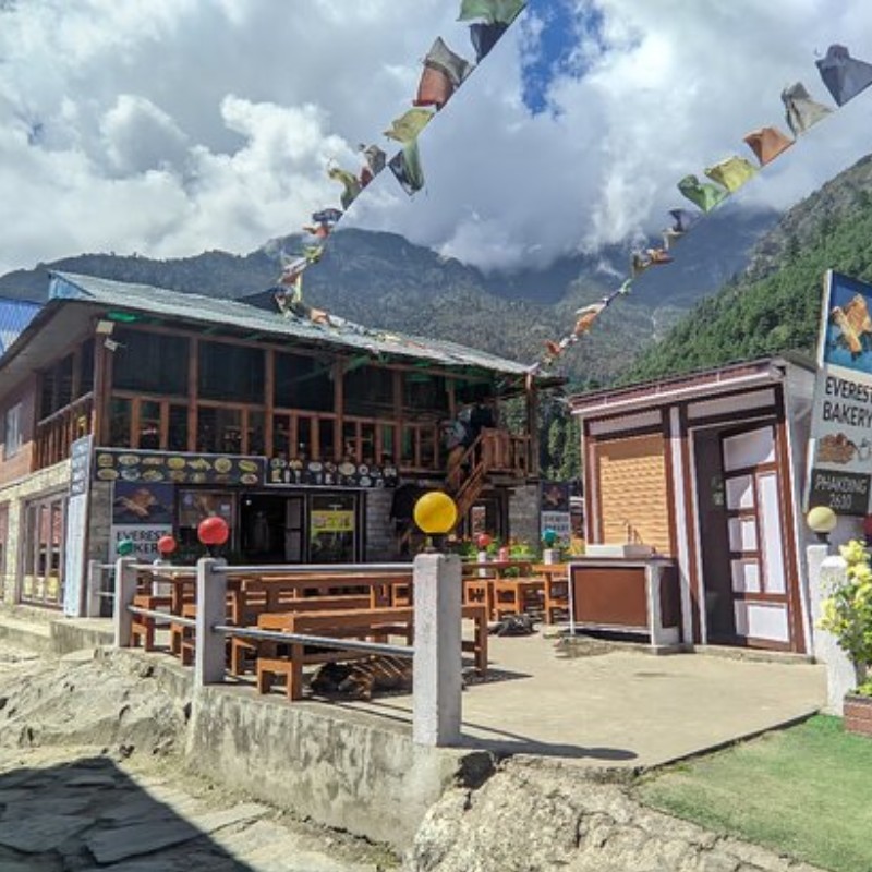Everest Bakery in Phakding with outdoor seating and prayer flags overhead