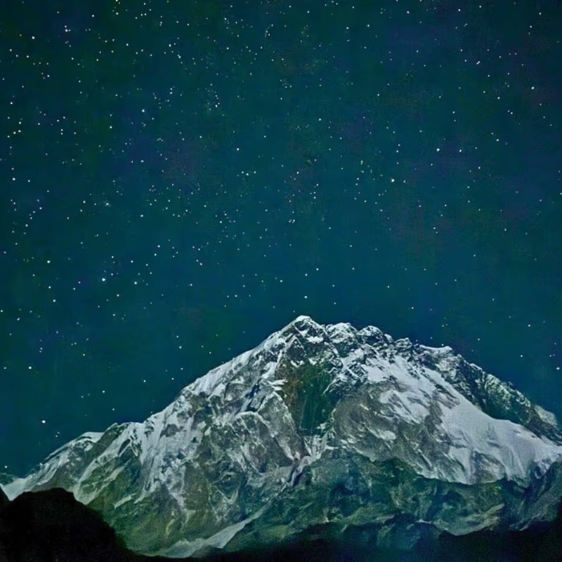 Snow-covered Himalayan peak beneath a star-filled night sky in Lobuche, Everest region.