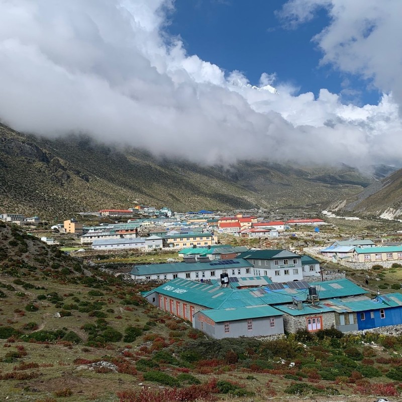 Dingboche village with colorful lodges beneath dramatic clouds in the Everest Himalayan valley.