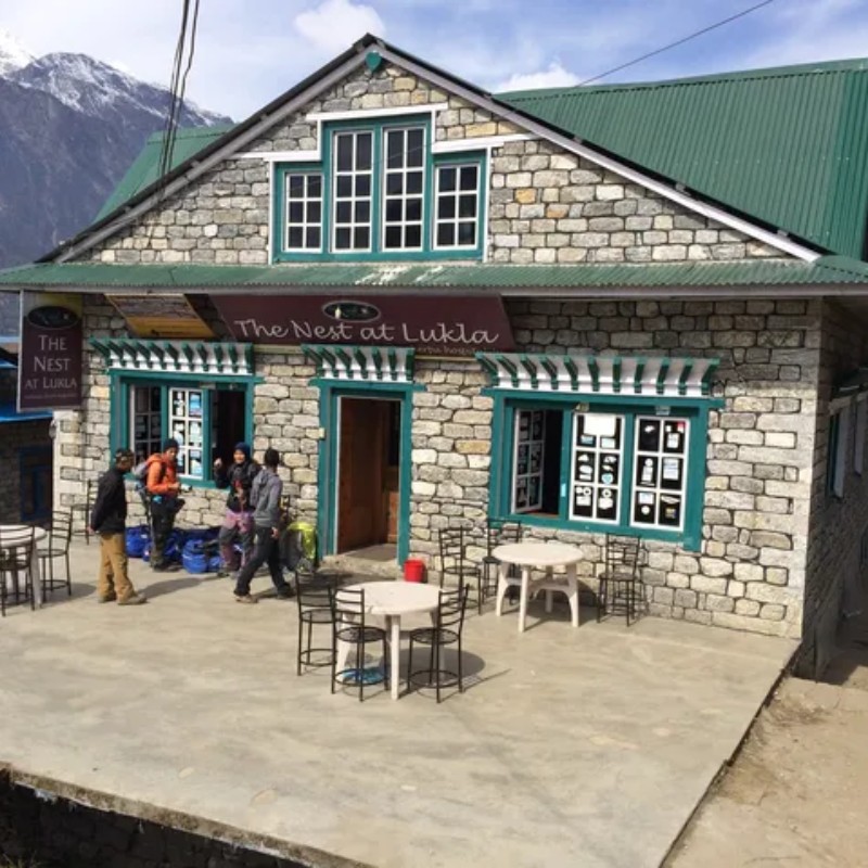 The Nest at Lukla lodge with trekkers standing outside the stone building