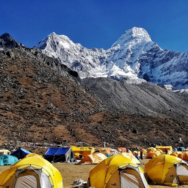 Colorful expedition tents at Ama Dablam Base Camp beneath towering snowy Himalayan peaks.